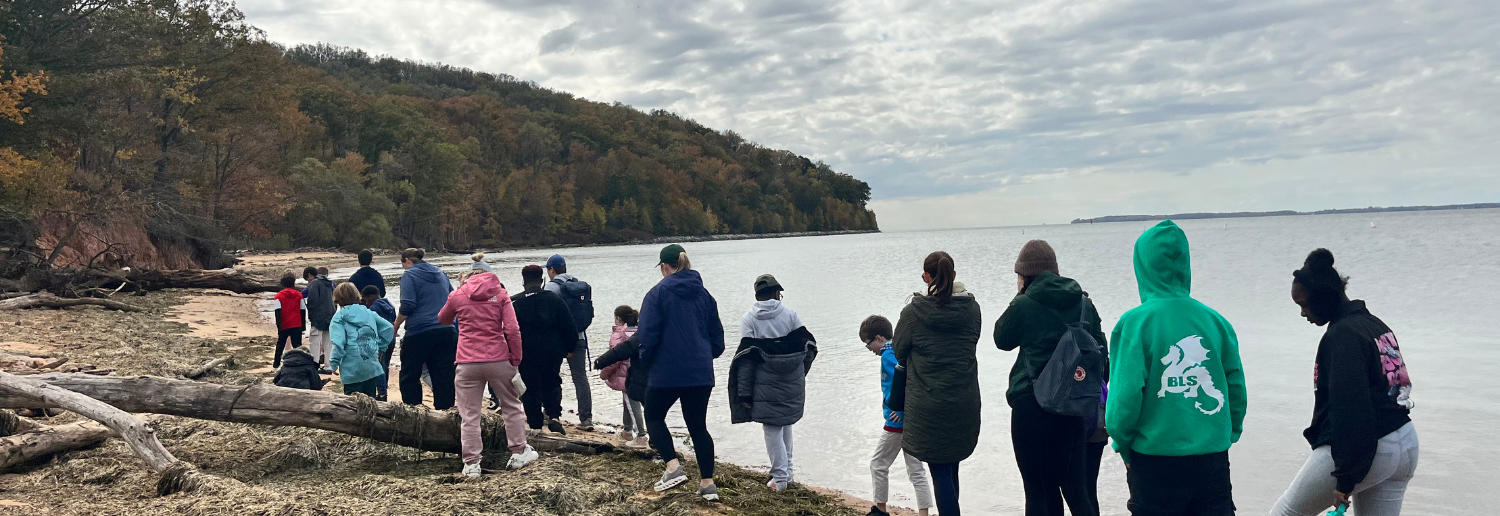 Baltimore Lab students and staff walk on a beach during an outdoor education trip.